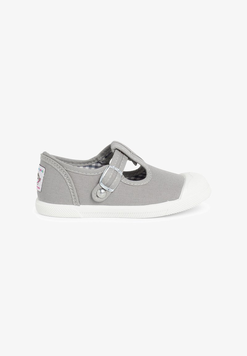 Zapato de lona gris con diseño de tira en T, suela de goma blanca, detalle de hebilla plateada y patrón interior a cuadros.