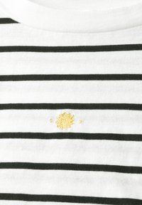 Biała bawełniana koszula z czarnymi poziomymi paskami. Posiada mały, haftowany emblemat żółtego słońca na obszarze klatki piersiowej. Klasyczny okrągły dekolt.