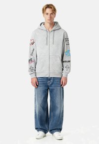 Hall hall lukuga dressipluus mitmete graafikute ja tekstidega varrukatel. Kombineeritud lahtiste siniste teksade ja valgete tossudega.