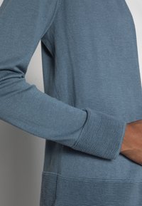 Hellblauer Strickcardigan mit langen Ärmeln, gerippten Bündchen und strukturiertem Saum. Verfügt über glattes Gewebe mit einem klaren, minimalistischen Design.