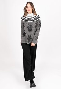 Gray sweater with black floral patterns, a white and black patterned yoke, paired with black wide-leg pants and black platform boots.