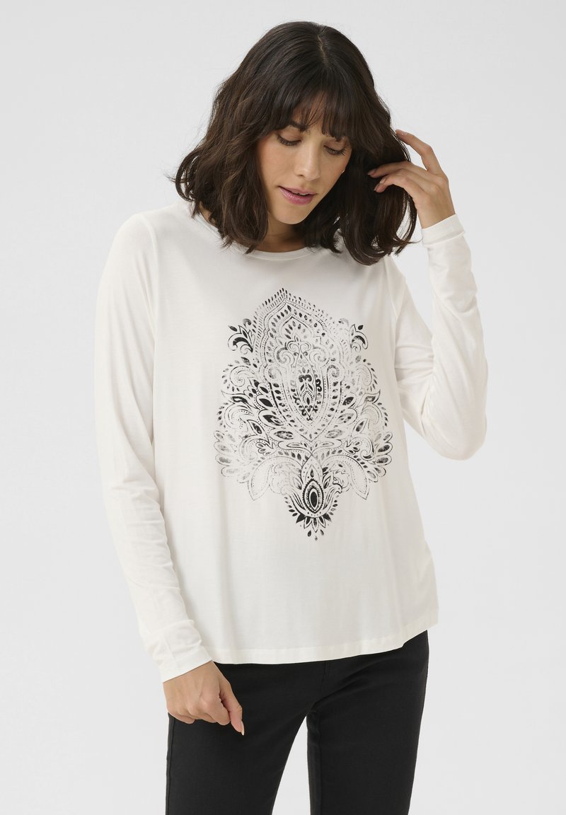 Long-sleeve cream shirt with a black intricate paisley print at the center, round neckline, relaxed fit, and soft texture.