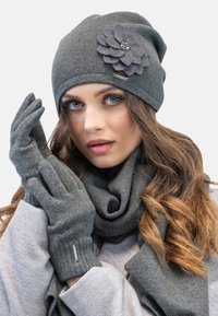 Cappello di lana grigio con un accento floreale in tessuto, guanti abbinati e una sciarpa; tutti con una finitura testurizzata, adatti per l'abbigliamento invernale.