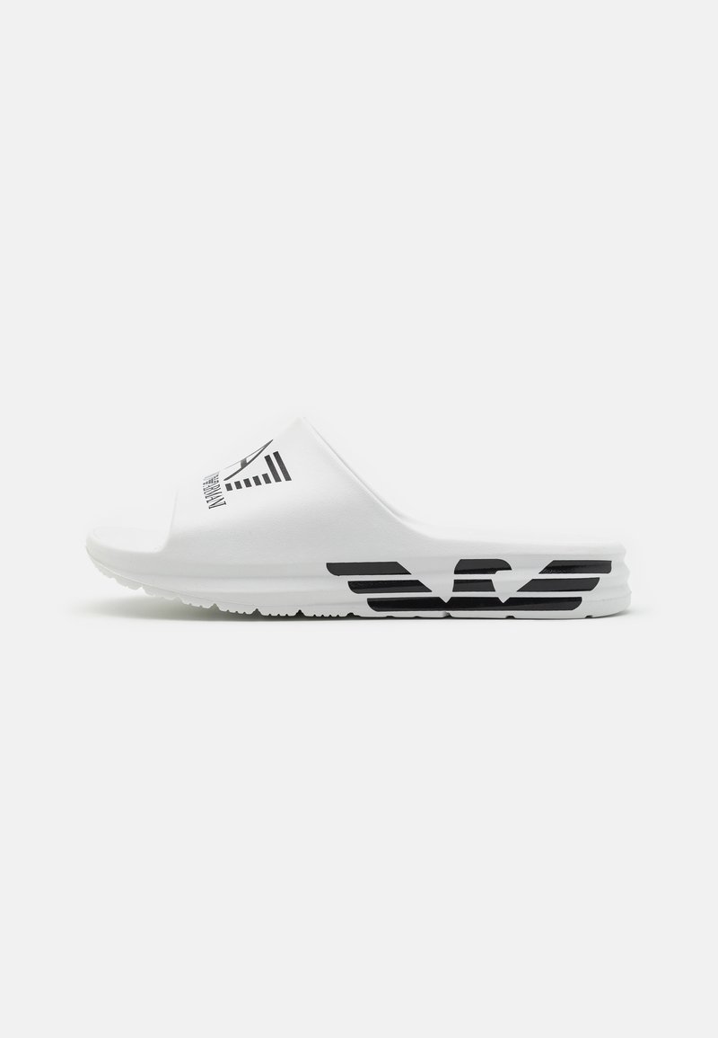 Sandalino bianco con una texture liscia, forma curva e un design grafico nero sulla fascia superiore. La suola presenta linee orizzontali nere.