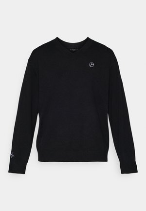 Suéter negro con cuello en V hecho de una tela suave, con mangas largas. En el pecho izquierdo tiene un pequeño logotipo circular; bordado sutil en la manga izquierda.