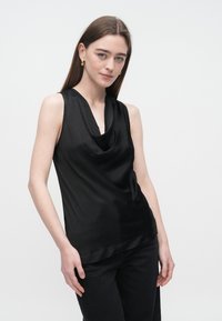 Top preto sem mangas com decote drapeado, confeccionado em tecido suave e texturizado, apresentando um corte descontraído e brilho subtil.