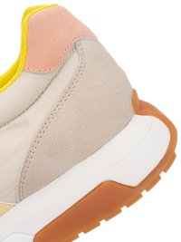 Close-up of beige and peach sneaker heel with yellow lining and white sole featuring an orange rubber outsole tread.