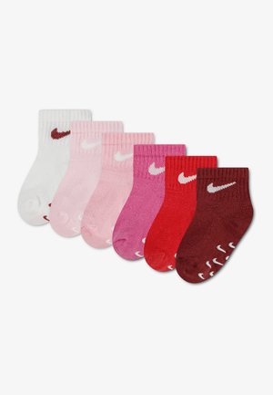 Šesť párov malých Nike členkových ponožiek v bielej, svetloružovej, ružovej, tmavoružovej, červenej a bordovej farbe s bielymi alebo tmavočervenými logami.