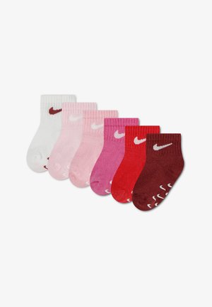 Six paires de petites chaussettes basses Nike en blanc, rose clair, rose, rose foncé, rouge et bordeaux avec des logos blancs ou rouge foncé.