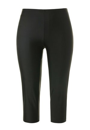 Zwarte capri leggings gemaakt van rekbaar, glad materiaal met een hoge tailleband en zonder zichtbare naden of patronen. De lengte eindigt net onder de kuit.