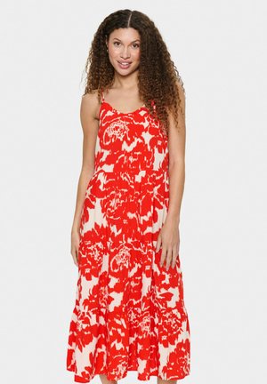 Robe maxi à motif floral rouge et blanc, en tissu léger, avec des bretelles spaghetti et un ourlet à volants superposés.