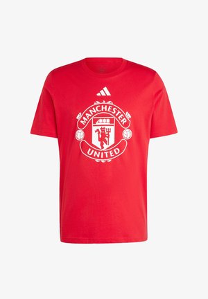 Röd bomullströja med en framträdande vit Manchester United-logotyp och Adidas-logotypen på den övre framsidan. Korta ärmar, rund halsdesign.