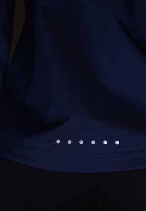 Ciemnoniebieska tkanina z siedmioma małymi, równomiernie rozmieszczonymi, odblaskowymi srebrnymi kropkami ułożonymi poziomo w pobliżu dolnej krawędzi.