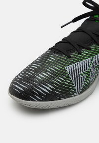Sort sportsko med tekstureret overflade, der har grønne og grå bølgemønstre. Gummisål i letvægtsmateriale og snøre-design.