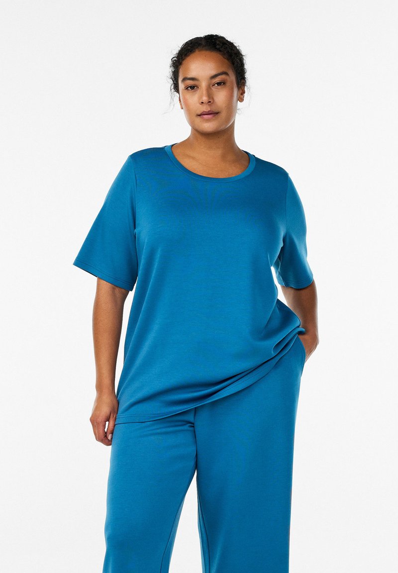 Volné petrolejové domácí oblečení z měkké látky, s kulatým výstřihem a krátkými rukávy, doplněné o kalhoty ve stejném odstínu a s minimálním zdobením.