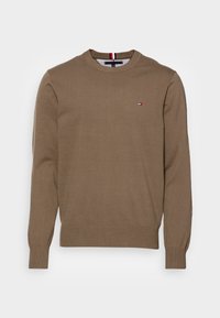 Bruine gebreide trui met lange mouwen, geribde boorden en een ronde hals. Voorzien van een klein logo op de linkerborst. Klassieke pasvorm en textuur.