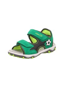 Zielone zamszowe sandały z czarnymi akcentami z siatki, regulowane paski na rzep, detal piłki nożnej oraz teksturowana biała i szara podeszwa z zielonymi akcentami.