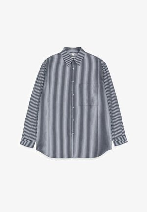 Skjorte med knapper foran med lodrette navyblå og hvide striber, krave, lange ærmer og brystlomme. Fremstillet af et letvægtsstof.