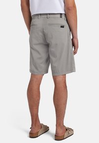 Pantaloni corti grigi chiari con una vestibilità morbida, realizzati in cotone, dotati di due tasche posteriori, cuciture sottili e orlo pulito. Indossati con sandali beige.
