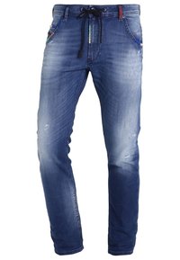Jeans slim fit azules desgastados con ligero deterioro, cintura con cordón y bolsillos frontales con detalles de ribete colorido.