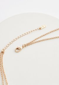 Gold-colored chain necklace with two different chain styles; features a lobster clasp and an adjustable link for length modification.