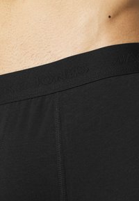 Zwarte katoenen boxershorts met een gestructureerde tailleband met gegraveerd merk. Glad stof met zichtbare stiksels.