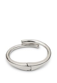 Pulsera de muñeca de metal tono plata con un acabado liso y pulido, y un diseño abierto único que presenta una punta afilada en un extremo.