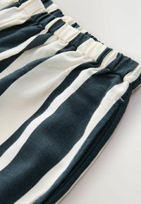 Randiga tygshorts med en smockad elastisk midja. Har alternerande mörkblå och krämfärgade ränder i ett mjukt, lätt material.