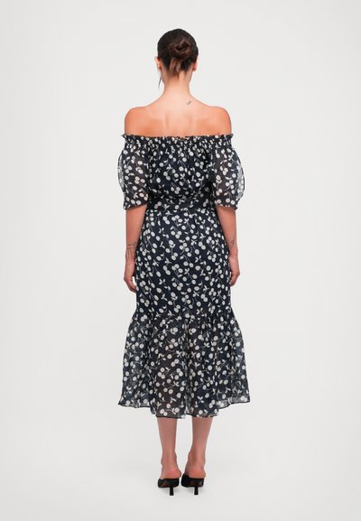 Marineblaues Blumenkleid mit schulterfreier Gestaltung, Puffärmeln und gestuften Rüschensaum. Mit weißen Blattmustern auf transparentem Stoff.