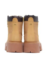 Stivaletti alla caviglia in pelle tan con colletto imbottito marrone e suole in gomma piatte. Presentano accessori in metallo dorato e dettagli in pelle cucita.