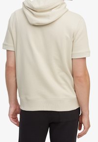 Felpa corta beige con maniche corte e cappuccio con coulisse. Tessuto morbido con una vestibilità rilassata, dotata di polsini a coste e orlo leggermente sagomato.