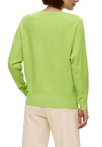 Limettengrüner, gerippter Strickpullover mit lockerer Passform, langen Ärmeln und rundem Ausschnitt. Die Textur ist glatt und das Design ist einfach.