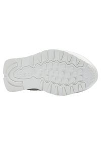 Semelle de chaussure blanche Reebok avec motifs de grip texturés et clous circulaires surélevés sous la semelle pour la traction et la stabilité.