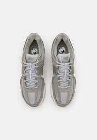 Baskets Nike Vomero avec une tige en mesh et synthétique de couleur grise et vert clair, accents blancs, lacets ronds et languette rembourrée.