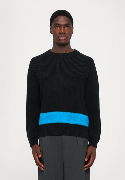 Sort strikket sweater med en tekstureret blå vandret stribe hen over midtsektionen. Løs pasform og rund halsudskæring.