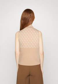 Top beige senza maniche con un retro in maglia testurizzata che presenta un delicato motivo logo. Tessuto liscio, vestibilità slim e scollo rotondo.