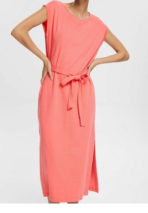 Korallinvärinen puuvillamekko, jossa on lyhyet hihat, solmittava vyö vyötäröllä, polven alapuolelle ulottuva helma ja sivulaskos lisäämässä liikkuvuutta. Sileä pinta, rento tyyli.