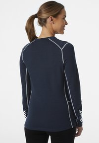 Granatowy, długi rękaw, pulower z kontrastowym białym ściegiem. Oferuje okrągły dekolt i paskowane akcenty na mankietach. Miękka faktura.