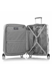 Valise grise avec un extérieur rigide, quatre roues, une poignée rétractable et des compartiments zippés à l'intérieur. Équipée de sangles croisées et de poches en mesh.