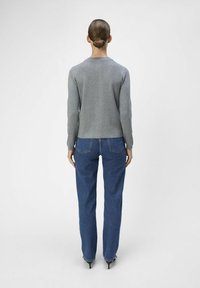 Grå langermet topp med rund hals, kombinert med blå vide jeans. Jeansene har en klassisk fem-lommers design og subtile sømdetaljer.