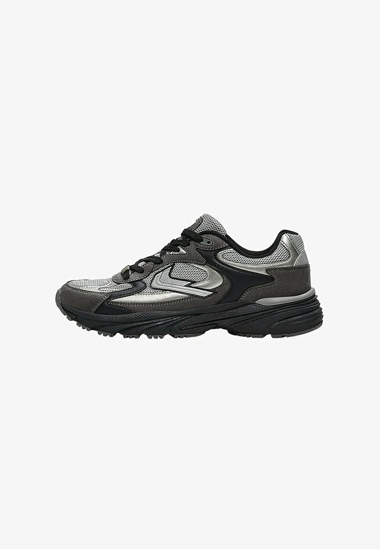Baskets de sport noires et argentées avec une tige en mesh et synthétique, lacets noirs et semelle épaisse texturée.