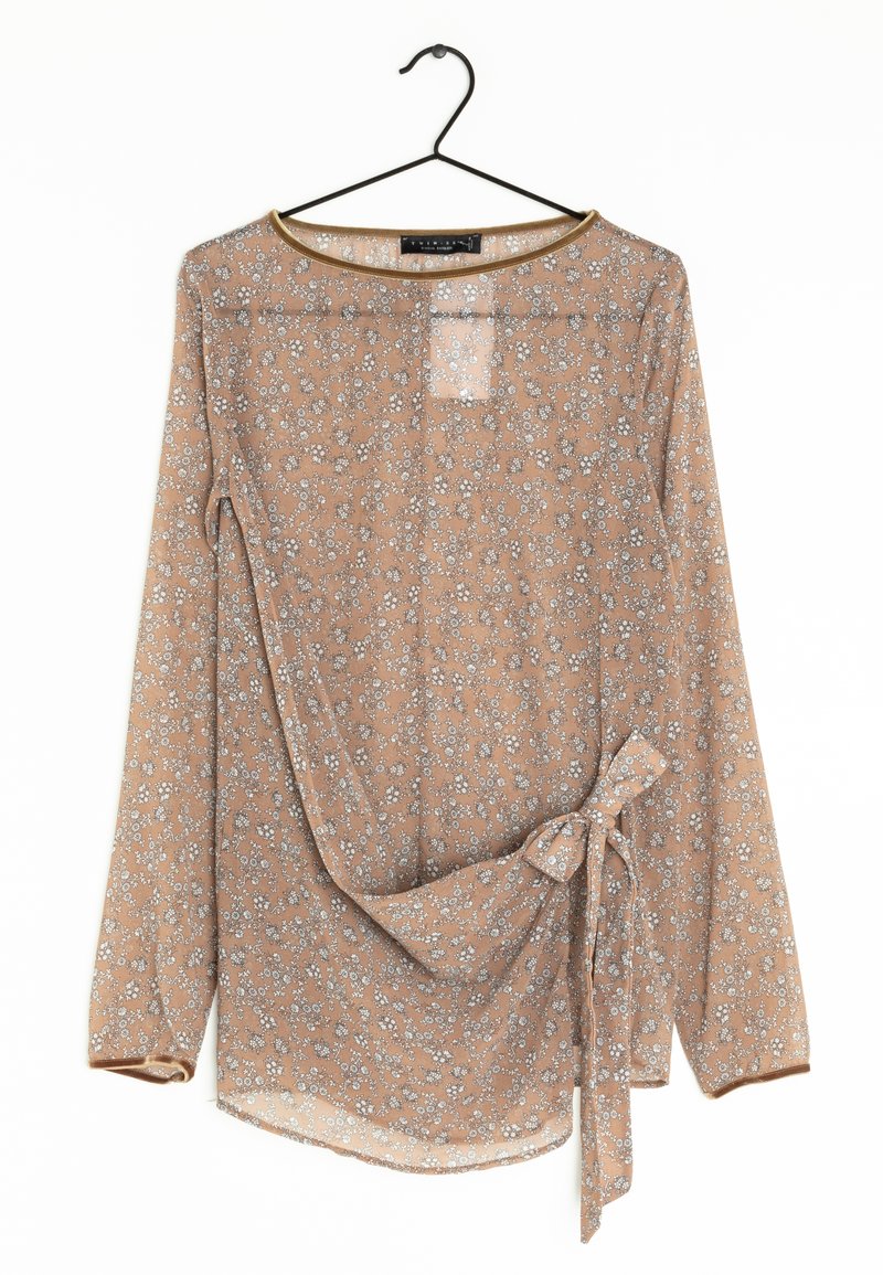 Blusa a maniche lunghe in tessuto sheer color marrone chiaro con piccolo motivo floreale bianco, dotata di un dettaglio con fiocco sul lato e collo rotondo.
