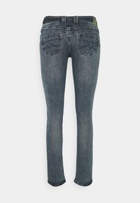 Vue arrière d'un jean en denim bleu slim avec des détails délavés et des poches arrière à double couture ornées de motifs ondulés.
