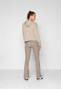 Under Armour MOTION FLARE PANT - Legíny - taupe dusk/black