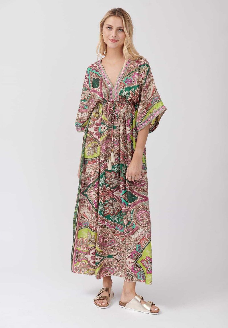 Robe maxi bohème multicolore avec des motifs paisley, décolleté en V, taille élastique, manches fluides et accents de franges décoratives.