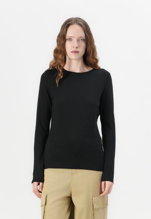 Svart langermet tettsittende topp med rund hals, laget av glatt stoff. Brukt med beige cargobukser, vist mot en hvit bakgrunn.