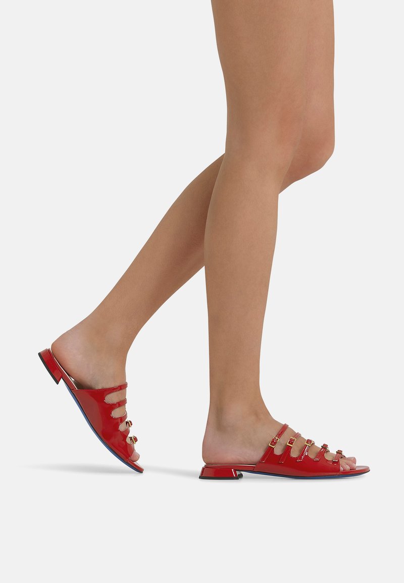 Sandali scivolati in pelle verniciata rossa con design open-toe, tre cinturini orizzontali decorati con dettagli oro e un tacco basso.