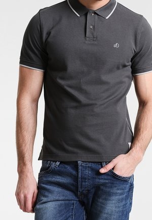 Polo gris foncé en coton, doté d'une patte à deux boutons, d'un col blanc et de bandes sur les manches, avec un petit logo sur la poitrine. Porté avec un jean bleu.