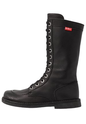 Bota de cuero negro hasta la rodilla con punta redonda, prominente cordón frontal, ojetes plateados y suela de goma texturizada. Logo de Kickers visible.