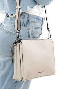 Light beige crossbody bag made of textured leather with black accents, featuring a zipper closure and a removable strap.